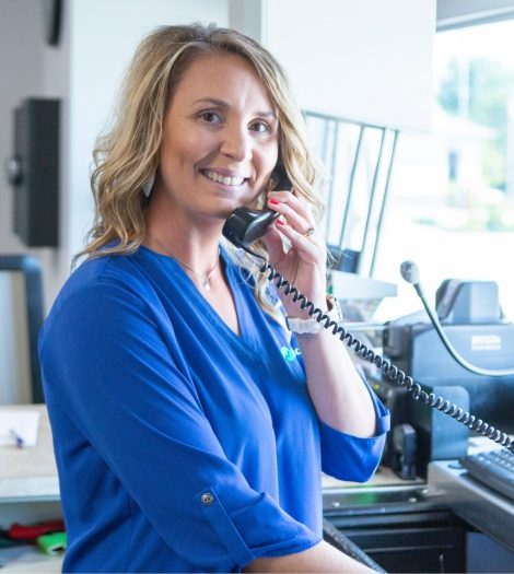 An employee is speaking over the phone with a customer in the drive-through line of a bank.