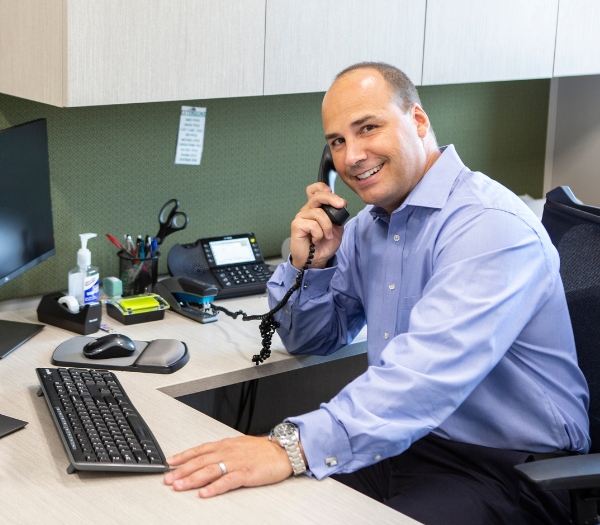 A businessman sits at a desk as he talks on the phone.