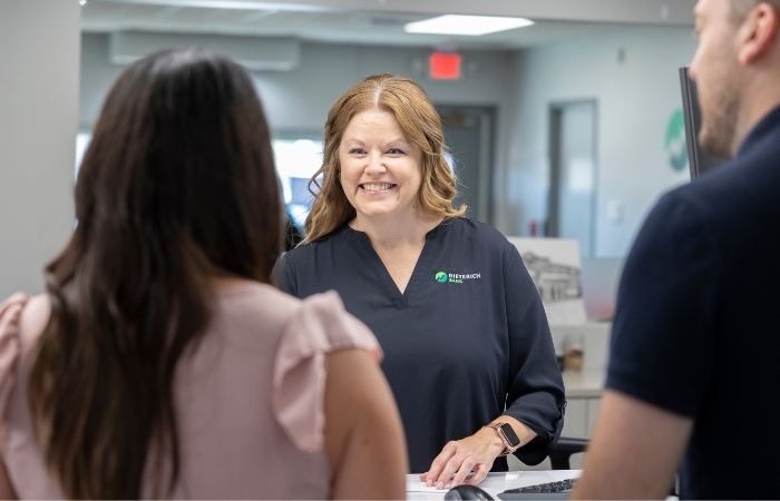 A female retail banker smiles as she helps customers at the front desk.