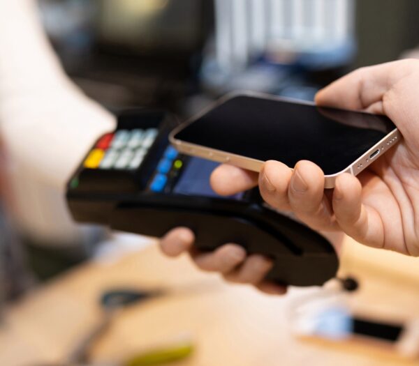 Consumer holding phone near card reader to use tap to pay.